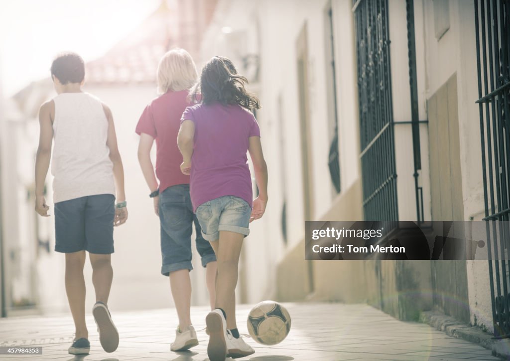 Niños jugando con pelota de fútbol en alley