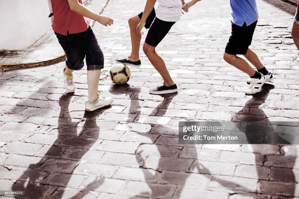 Children playing with soccer ball in alley