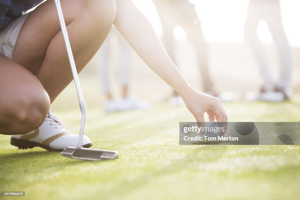 Woman removing golf ball from hole