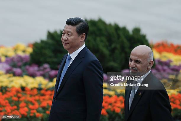 Chinese President Xi Jinping accompanies Afghan President Ashraf Ghani Ahmadzai to view an honour guard during a welcoming ceremony outside the Great...