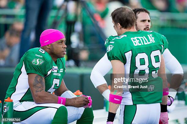Kerry Joseph talks with Chris Getzlaf and Brett Swain of the Saskatchewan Roughriders on the bench during the game between the Edmonton Eskimos and...