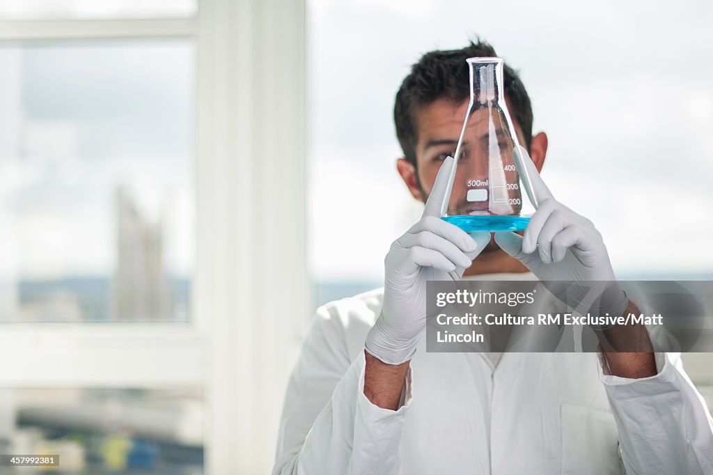 Medical student holding flask with blue liquid