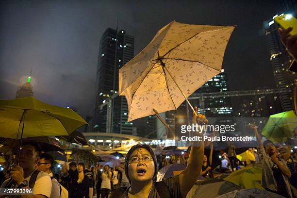 Protesters hold umbrellas and signs as thousands come to the main protest site one month after the Hong Kong police used tear gas to disperse...