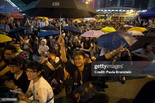 Protesters hold umbrellas as thousands come to the main protest site one month after the Hong Kong police used tear gas to disperse protesters...