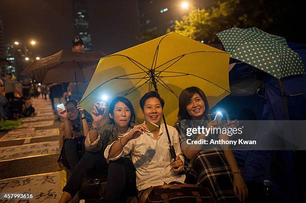 Pro-democracy protesters hold umbrellas in the air and wave their cell phone lights as they sing songs outside of Hong Kong Government Complex on...