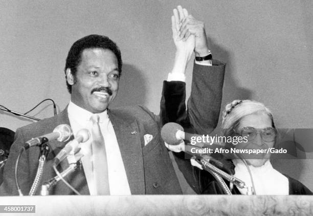 Civil Rights leader Jesse Jackson Sr and activist Rosa Parks raise their hands triumphantly during a speech, 1965.