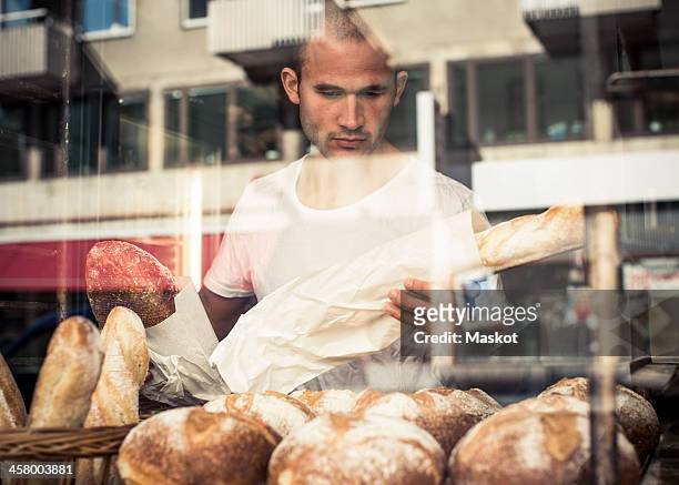 view of mid adult male owner working at bakery through display cabinet - facade works stock pictures, royalty-free photos & images
