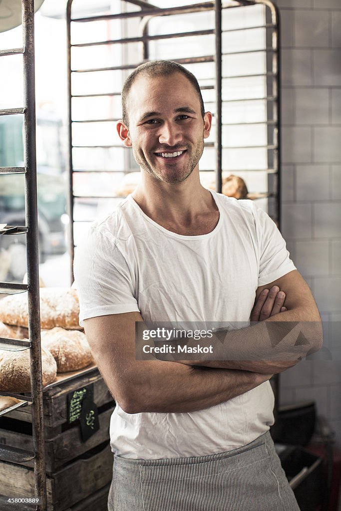 Portrait of confident male owner standing arms crossed in bakery