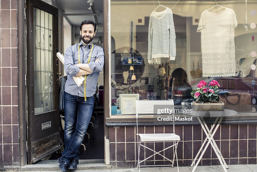 Portrait of confident mid adult male designer standing at studio entrance