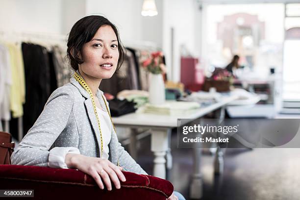 portrait of confident female fashion designer sitting in studio - modedesigner stock-fotos und bilder