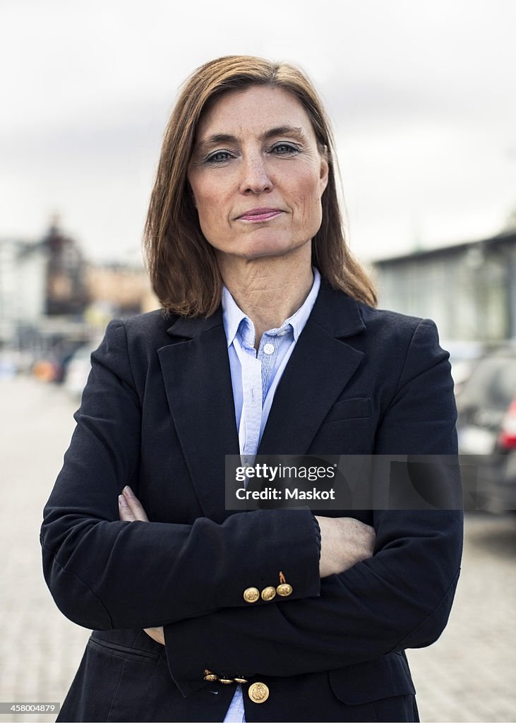 Portrait of confident mature businesswoman standing arms crossed on street