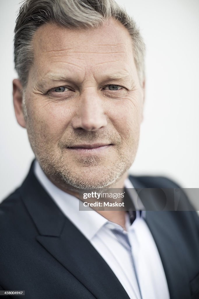 Close-up portrait of confident mature businessman against clear sky