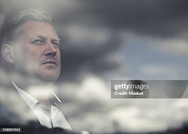 reflection of clouds on glass window while businessman looking away - thinking man cloud stockfoto's en -beelden