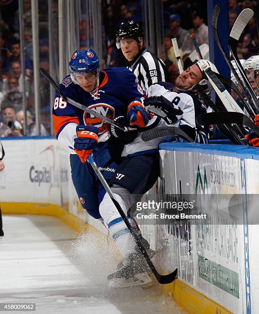 Nikolai Kulemin of the New York Islanders hits Mark Stuart of the Winnipeg Jets into the boards during the first period at the Nassau Veterans...