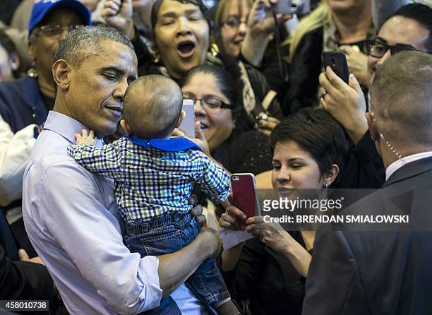 President Barack Obama holds a baby after a rally at North Division High School October 28, 2014 in Milwaukee, Wisconsin. Obama joined the rally to...