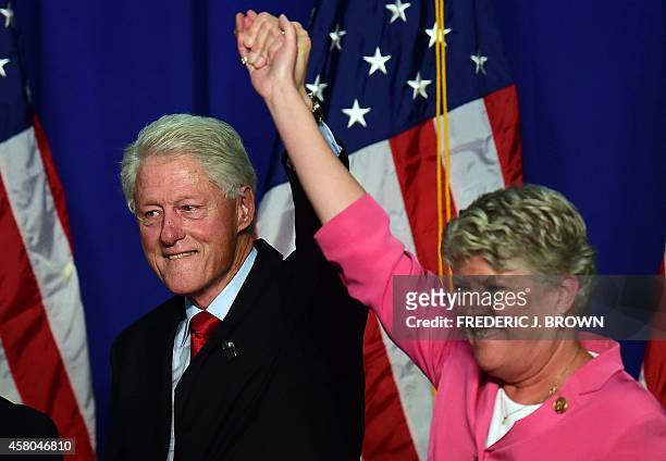 Former US President Bill Clinton lifts the arm of California Congresswoman Julia Brownley in a show of support during a "Get Out The Vote" rally in...