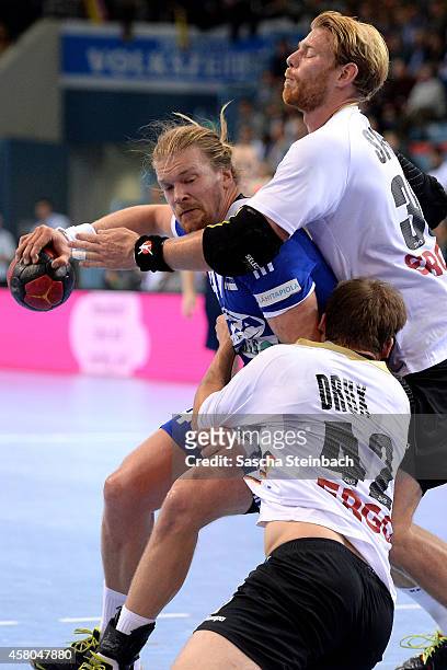 Leonel Henrik Ojala of Finland is tackled by Paul Drux and Manuel Spaeth of Germany during the 2016 European Men's Handball Championship qualifier...