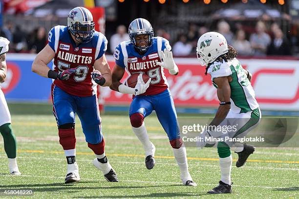 Duron Carter of the Montreal Alouettes runs with the ball as teammate Josh Bourke tries to protect him from Weldon Brown of the Saskatchewan...