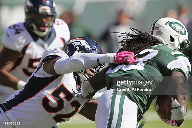 Running Back Chris Ivory of the New York Jets is stopped by Linebacker Corey Nelson of the Denver Broncos at MetLife Stadium on October 12, 2014 in...