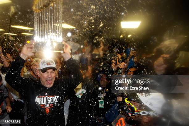 Bruce Bochy of the San Francisco Giants celebrates with The Commissioner's Trophy in the locker room after a 3-2 win over the Kansas City Royals in...