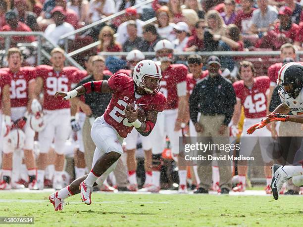 Barry Sanders, a running back for the Stanford University Cardinal, runs with the ball in a rain shower during a PAC-12 NCAA football game against...