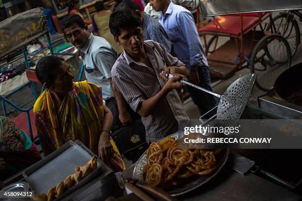 In this photograph taken on October 27 an Indian worker at Old Famous Jalebi Wala, which sells jalebi sweets and samosas, makes fresh jalebis, fried...