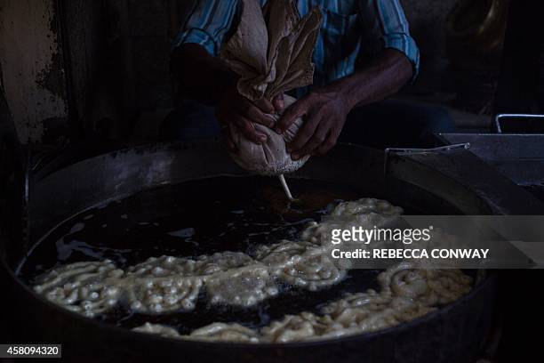 In this photograph taken on October 27 an Indian worker at Old Famous Jalebi Wala, which sells jalebi sweets and samosas, makes fresh jalebis, fried...
