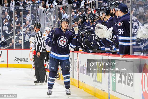 Mark Scheifele of the Winnipeg Jets gets congratulated by teammates at the bench after scoring a first period goal against the Calgary Flames on...