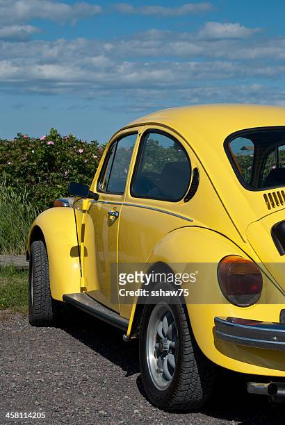 bright yellow volkswagen beetle in parking lot - new beetle stock pictures, royalty-free photos & images