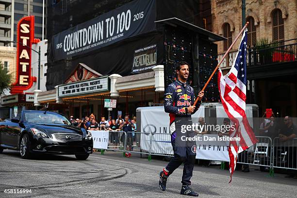 Daniel Ricciardo of Australia and Infiniti Red Bull Racing waves an American national flag along North Congress Avenue backdropped by the Texas...