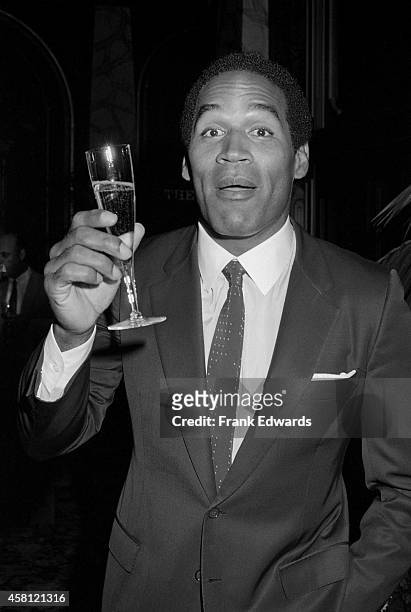 Former NFL player O.J. Simpson poses for a portrait with a glass of champagne at the "Hotel" TV party on October 24, 1985 in Burbank, California.