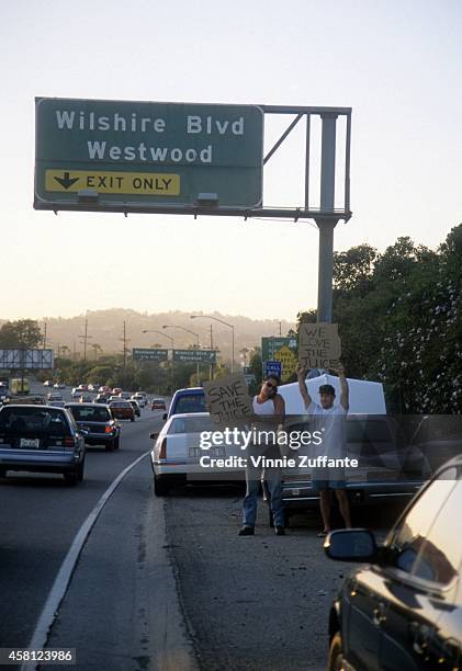 Motorists wave signs as police cars pursue the Ford Bronco driven by Al Cowlings, carrying fugitive murder suspect O.J. Simpson, on a 90-minute...