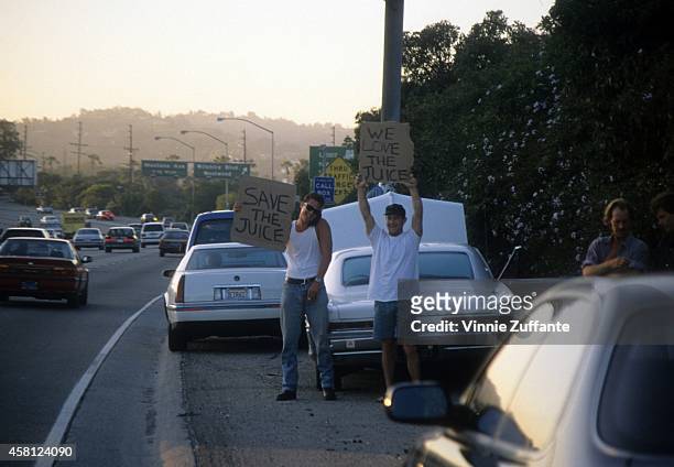 Motorists wave signs as police cars pursue the Ford Bronco driven by Al Cowlings, carrying fugitive murder suspect O.J. Simpson, on a 90-minute...