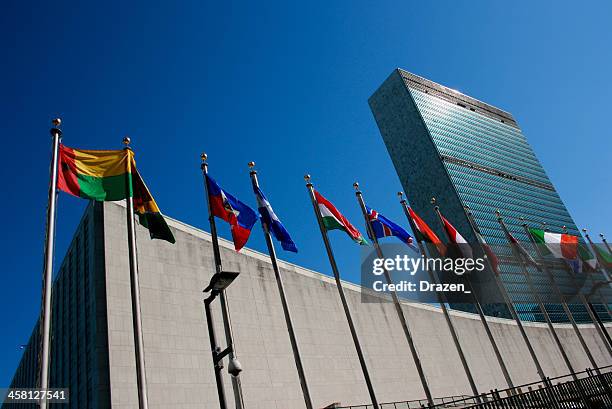 united nations headquarters with waving flags in new york, usa - united nations building flags stock pictures, royalty-free photos & images