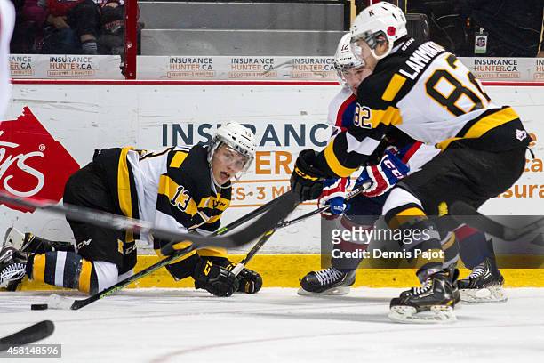 Juho Lammikko and Jarkko Parikka of the Kingston Frontenacs battle for the puck against Jamie Lewis of the Windsor Spitfires on October 30, 2014 at...
