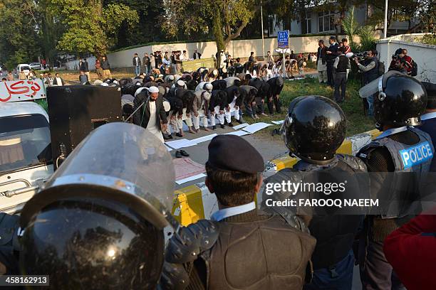 Pakistani civil society and Jamaat-e-Islami party activists pray during a protest outside the Bangladeshi embassy in Islamabad on December 20 against...