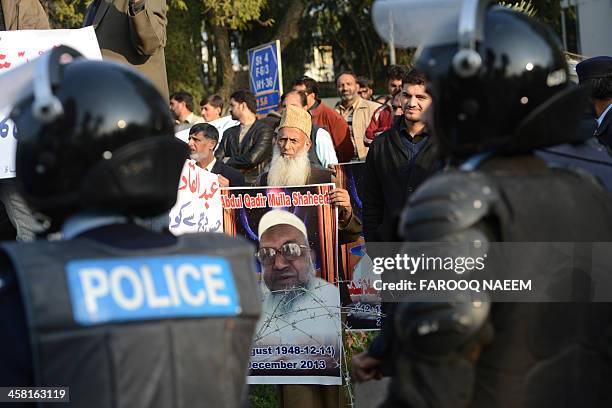 Pakistani policeman stands guard as civil society and Jamaat-e-Islami party activists protest outside the Bangladeshi embassy in Islamabad on...