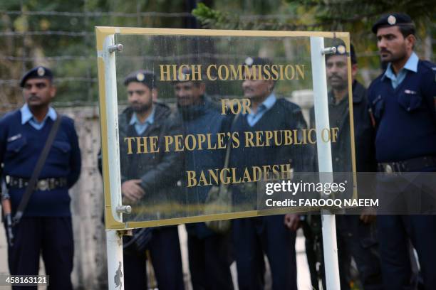 Pakistani policemen stand guard as civil society and Jamaat-e-Islami party activists protest outside the Bangladeshi embassy in Islamabad on December...