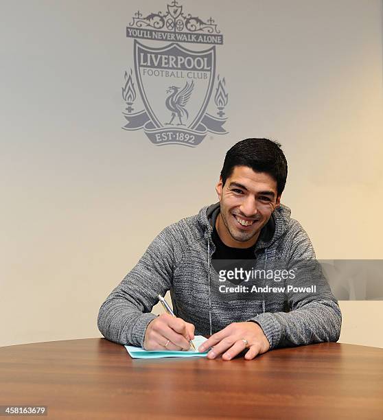 Luis Suarez of Liverpool poses for a photo whikle signing a new long term contract for the club at Melwood Training Ground on December 20, 2013 in...