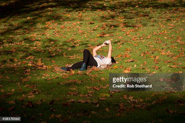 Woman relaxes in the sunshine in Green Park on October 31, 2014 in London, England. Temperatures in London are forecasted to exceed 20 degrees making...