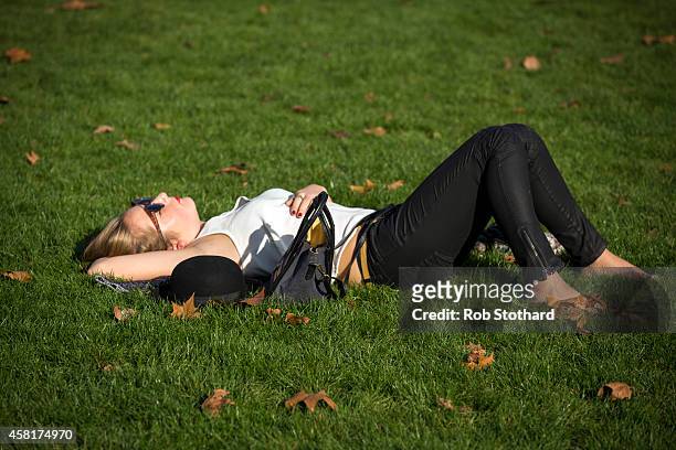 Woman relaxes in the sunshine in Green Park on October 31, 2014 in London, England. Temperatures in London are forecasted to exceed 20 degrees making...