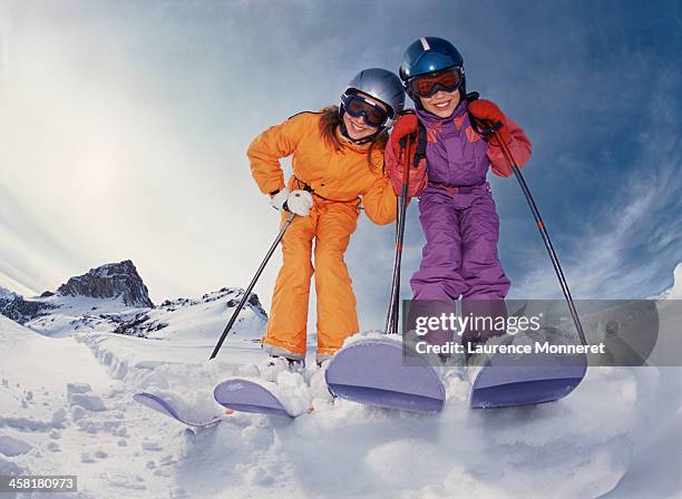 smiling skiing kids posing with helmets - family in snow mountain stock-fotos und bilder