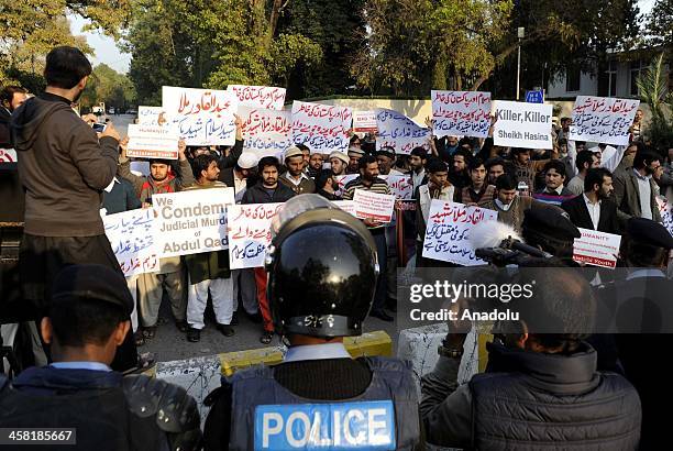 Pakistani policemen stand guard as members of Jamaat-e-Islami Pakistan stage a protest outside the Bangladesh high commission to condemn the...