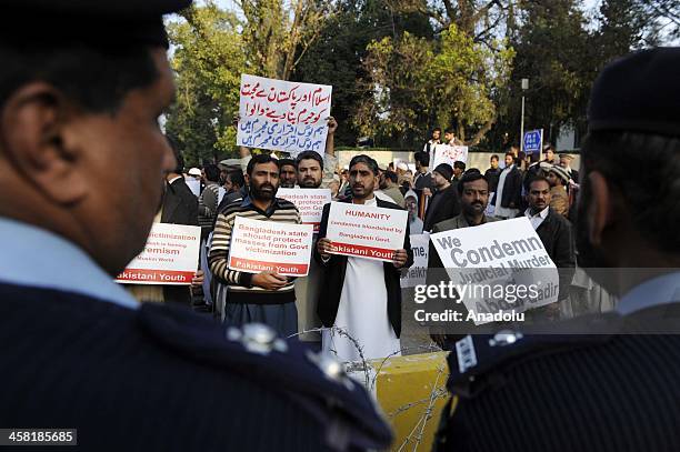 Pakistani policemen stand guard as members of Jamaat-e-Islami Pakistan stage a protest outside the Bangladesh high commission to condemn the...