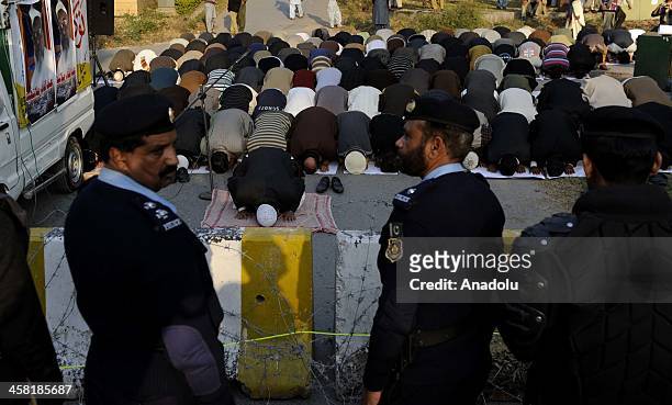 Pakistani policemen stand guard as members of Jamaat-e-Islami Pakistan perform prayer during a protest outside the Bangladesh high commission to...
