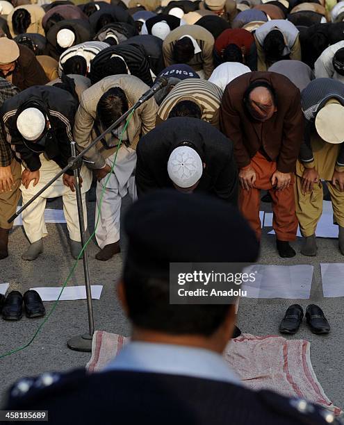 Pakistani policemen stand guard as members of Jamaat-e-Islami Pakistan perform prayer during a protest outside the Bangladesh high commission to...