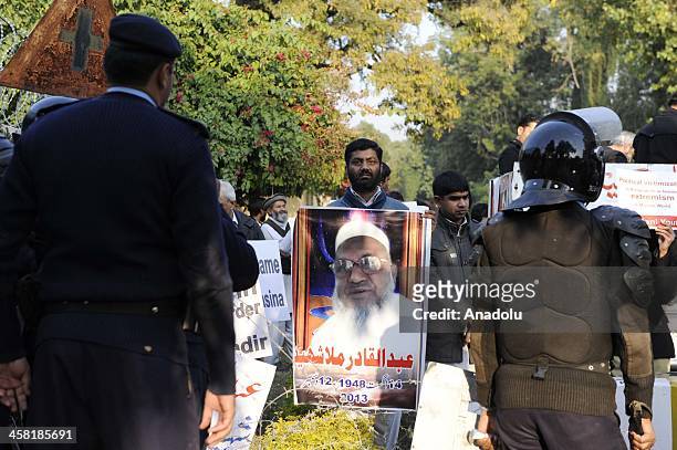 Pakistani policemen stand guard as members of Jamaat-e-Islami Pakistan stage a protest outside the Bangladesh high commission to condemn the...