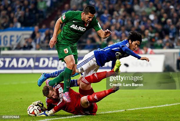 Raul Bobadilla of Augsburg is challenged by Ralf Fahrmann of Schalke 04 and Atsuto Uchida of Schalke 04 during the Bundesliga match between FC...