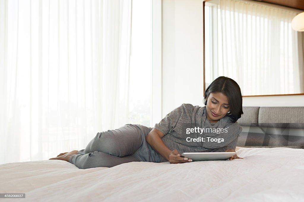 Woman on bed using digital tablet