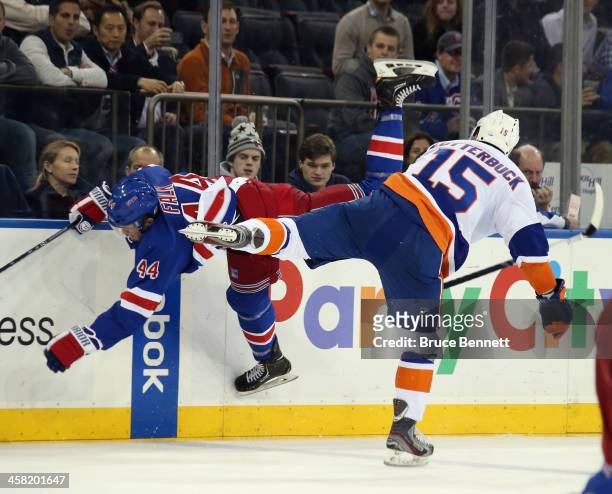 Cal Clutterbuck of the New York Islanders hits Justin Falk of the New York Rangers during the third period at Madison Square Garden on December 20,...